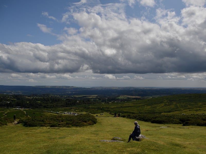 Dartmoor National Park has had 420,000 visitors and a 41 per cent increase from 2019. Pictured is a walker looking out towards Torbay as they rest at the foot of Haytor Rocks in the Dartmoor National Park.