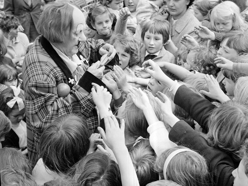 Coco the Clown, wearing a tartan suit, signs autographs for children in Princes Street in 1966.