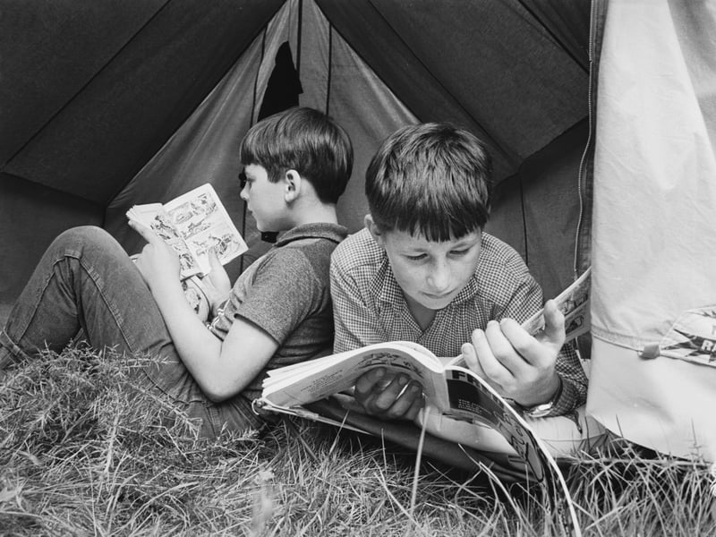 Two boys enjoying reading comics at a summer camp run by the National Association for Gifted Children in August 1967