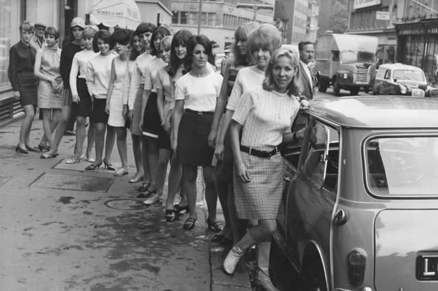Fifteen young women in mini skirts wait to board a BMC Mini in July 1966 to break the world record for passengers in a Mini