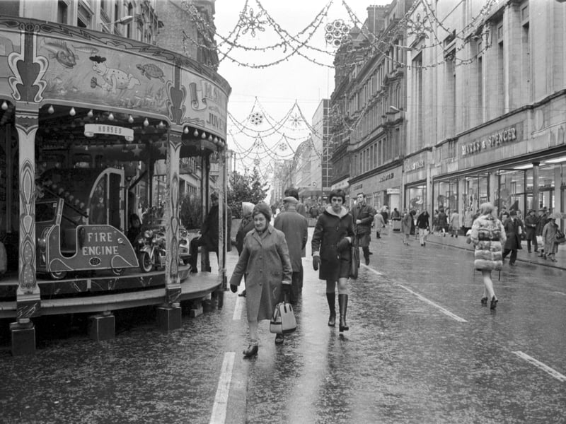 People doing Christmas shopping on a traffic-free Sauchiehall Street, Glasgow, in December 1972, with the festive carousel/funfair to the left