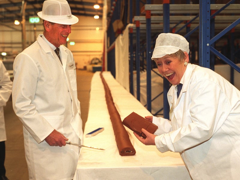 The Duke of Edinburgh cuts a slice from a 60ft swiss roll for Coronation Street's Liz Dawn at the opening of Oakdale Bakeries new factory.