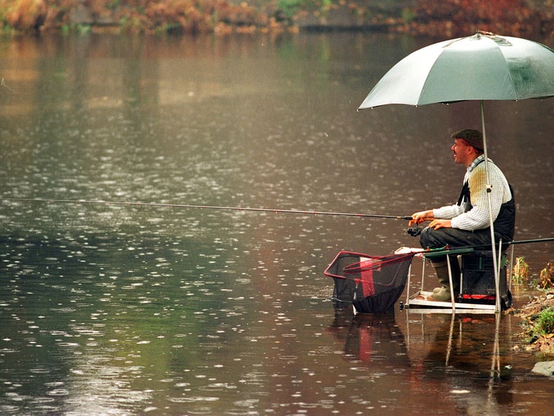 A fisherman waits patiently for a bite alongside the River Wharfe.