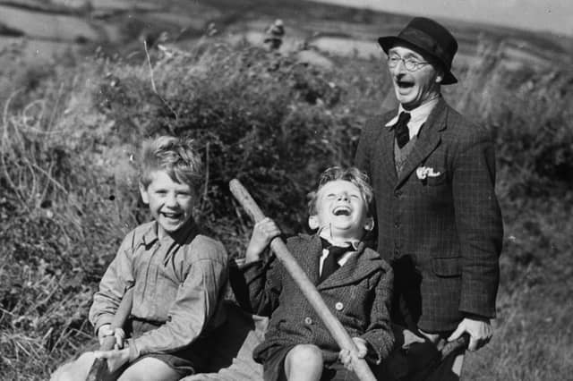 Two young boys evacuated to a farm in Devon enjoy a ride home in a wheelbarrow after a day's work in the fields in August 1941