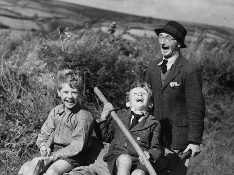 Two young boys evacuated to a farm in Devon enjoy a ride home in a wheelbarrow after a day's work in the fields in August 1941