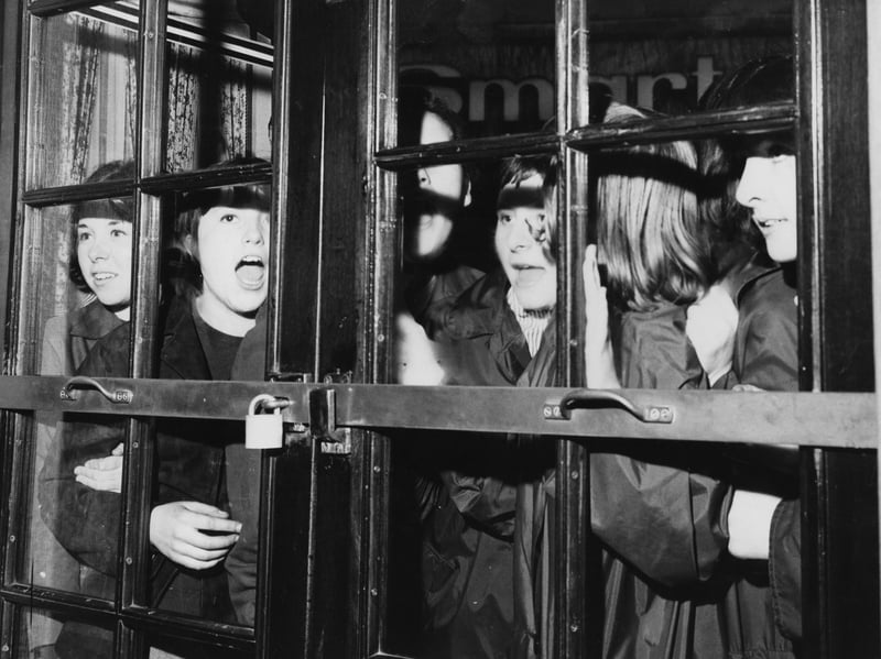 A group of girls bang and shout at the door of the Prince of Wales Theatre in London's West End, where The Beatles are rehearsing for the Royal Command Performance, in November 1963