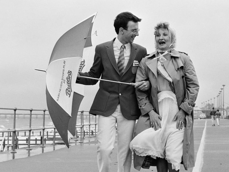 A Butlins Redcoat and the winner of the camp's glamorous grandmother competition walk along the seafront in Bognor Regis, West Sussex, on Friday, June 21, 1985