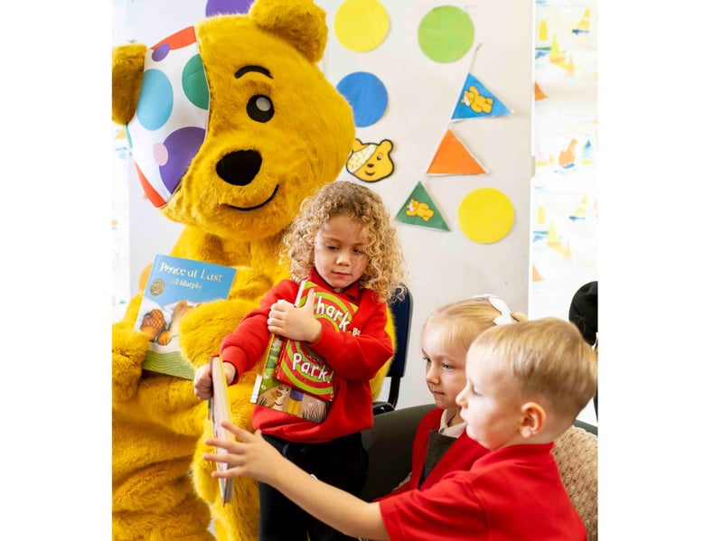 Pudsey helps children to choose a storybook.