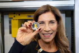 Freddie Mercury's sister, Kashmira Bulsara, holding the new Royal Mint commemorative coin. The design features Mercury mid-performance, his signature, and details like his Live Aid outfit (Photo: Royal Mint)