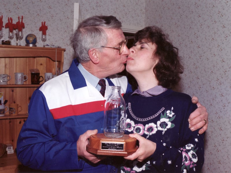A surprise for milkman, Jim Wright, on his last day making deliveries on Langdon Street, Sharrow, Sheffield, in April 1993, as he gets a farewell kiss from customer Caroline Wells, a gift of a mounted milk bottle, a celebration cake and wine
