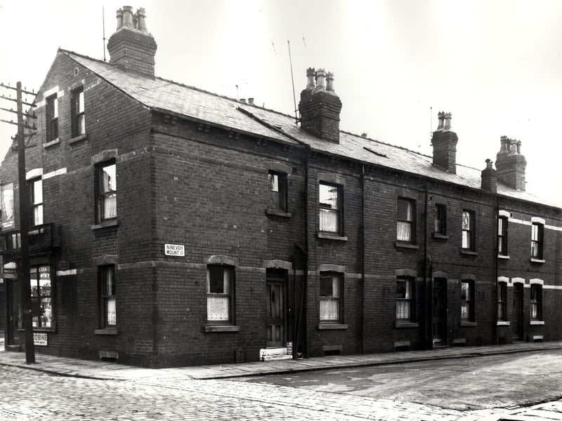 On the left edge of this view, part of a grocers shop at number 2 Nineveh Avenue is visible. Numbers 1 to 5 Nineveh Mount runs to the right. These are double fronted, back-to-back houses which were included in slum clearance plans for the Holbeck area. Pictured in November 1966.