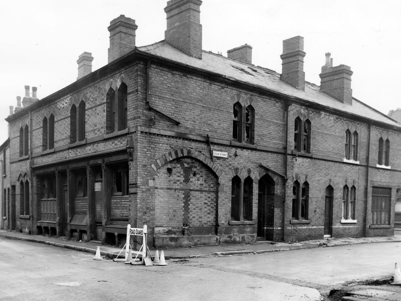 Bridge Road, a large building on the corner with Czar Street. Windows are smashed and certain sections have been boarded or bricked up. At the corner is a road guard and traffic cones warning of road works. Visible on the right are numbers 1 and 3 Czar Street. Pictured in November 1965.