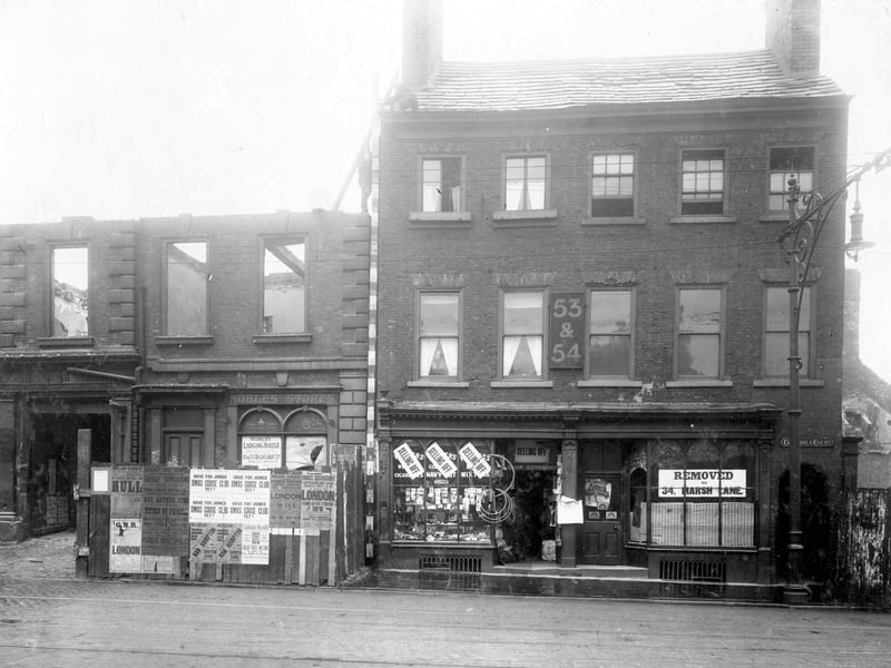 Kirkgate before improvement. To the right of photograph is the arched entrance to Croisdale Court. Next to this is the empty premises that was previously Illingworths Grindery Stores at 54 Kirkgate then E.Wray newsagents at 53 which has signs in window stating 'selling off'. Next door at 52 is the partly demolished premises that was previously Nobles Stores, with the entrance to Barstows Yard just visible. There are various posters pasted onto fence at front of Nobles stores.