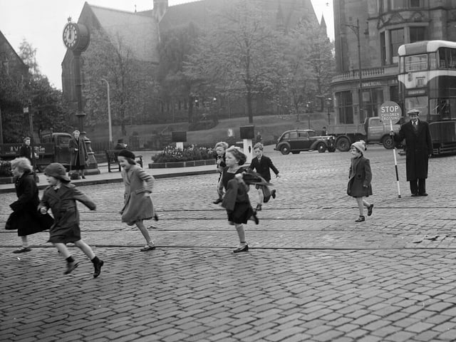 A lollipop man helps primary school children cross the street in Morningside after school comes out in 1954.