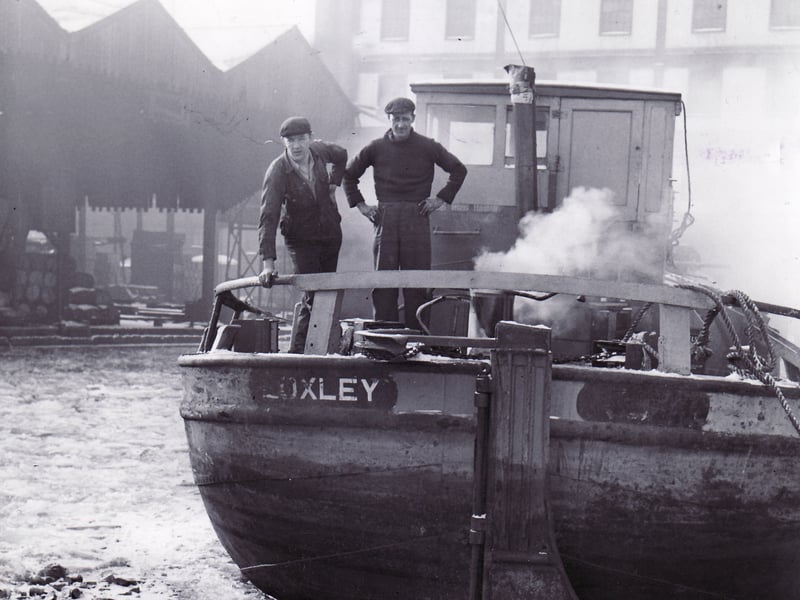 Hull bargee James Walker and engineer Brian Appleyard look over the stern of their barge, Loxley, which is ice-bound at Canal Wharf, Sheffield, in January 1963