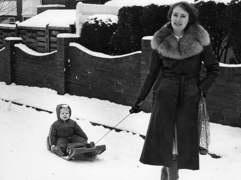 Margery Holmes leaves her pram at home and walks to the shops using a sledge to transport 17-month-old Neil in January 1982