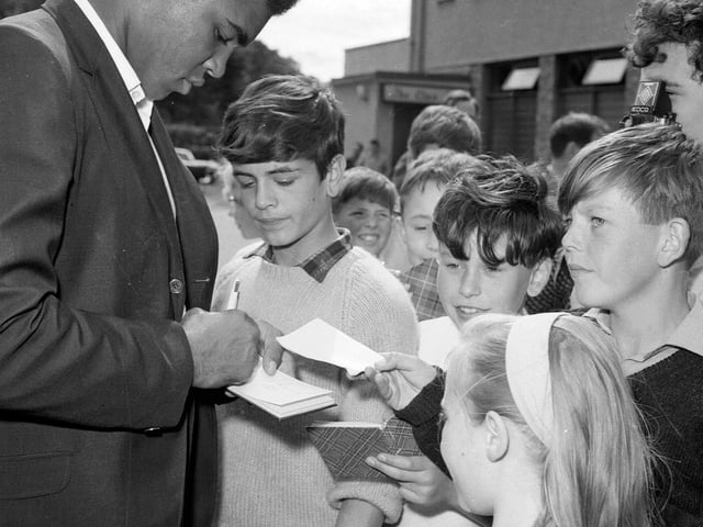 Muhammad Ali signs autographs for children on his arrival in Glasgow in 1965.