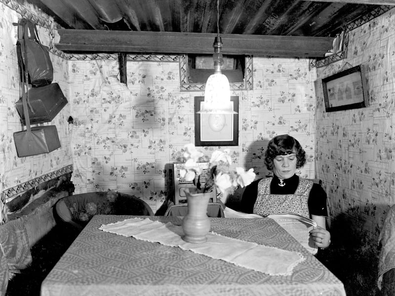 Gertrude Mabel Fawcett is pictured as she sits reading a magazine at her table in the strengthened coal cellar on Cardigan Avenue in October 1940. This air raid shelter was one of many in Leeds inspected by the A.R.P. Committee and the chairman, Councillor H. W. Sellers, praised the couple in a report which appeared in the Yorkshire Evening News.