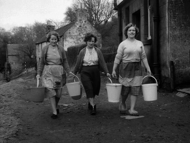 Housewives carry water in buckets after frozen pipes led there to be now water available at Caddell Road in Cramond in March 1963.