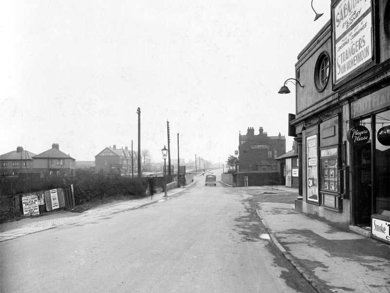 Station Road, across the railway bridge before it was widened. Houses to the left are on Coldwell Road. To the right, the Station Hotel, a Tetleys' public house. Next, entrance to Cross Gates station for London and North Eastern railway line between Leeds and York. The side of the Ritz cinema can be seen. Pictured in April 1937.