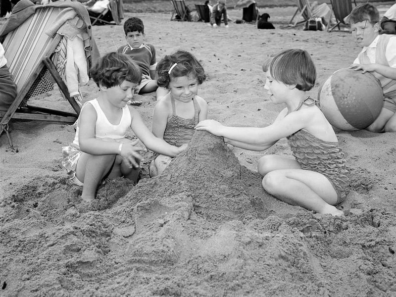 Three girls building a sandcastle on Cramond Beach, in August 1954.