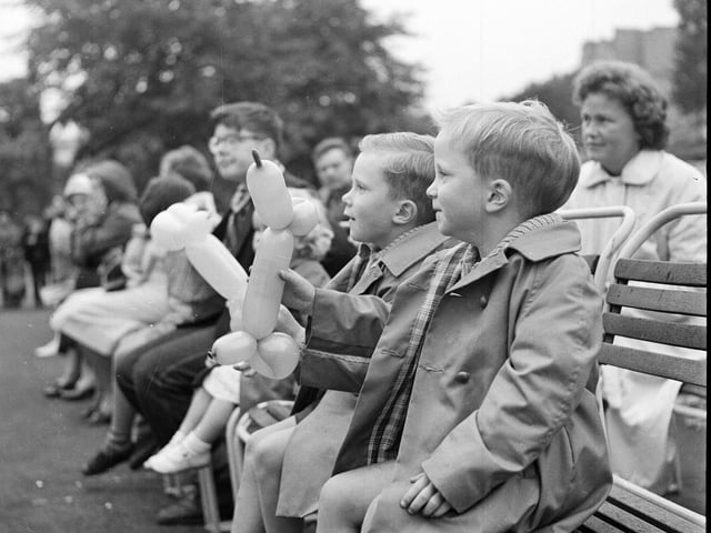 Twin boys with balloon animals watching the Princes Street Gardens Punch and Judy show at the Ross Bandstand in 1963.