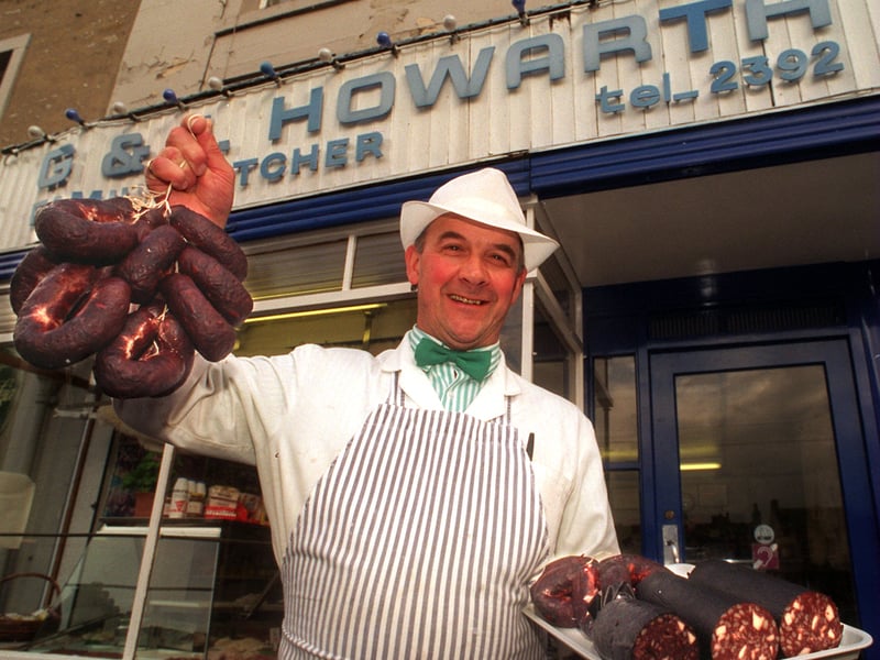 George Howarth outside his family butcher's shop in Settle, holding up his award-winning black puddings, in 1995