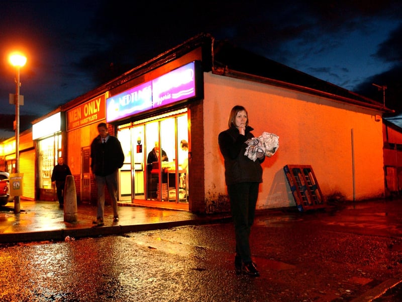 A woman leaves a fish and chip shop in Glasgow with a fish supper in 2002