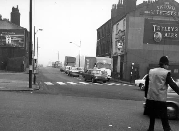A view from November 1968 looking north-east at numbers 8 to 14 Roundhay Road (on the right). Number 8 is the Victoria pub, which has signs advertising Tetley's Ales. In the foreground, a traffic policeman directs cars and vans across the junction with Manor Street.