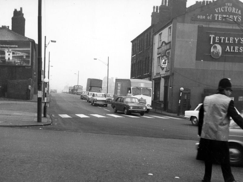 A view from November 1968 looking north-east at numbers 8 to 14 Roundhay Road (on the right). Number 8 is the Victoria pub, which has signs advertising Tetley's Ales. In the foreground, a traffic policeman directs cars and vans across the junction with Manor Street.