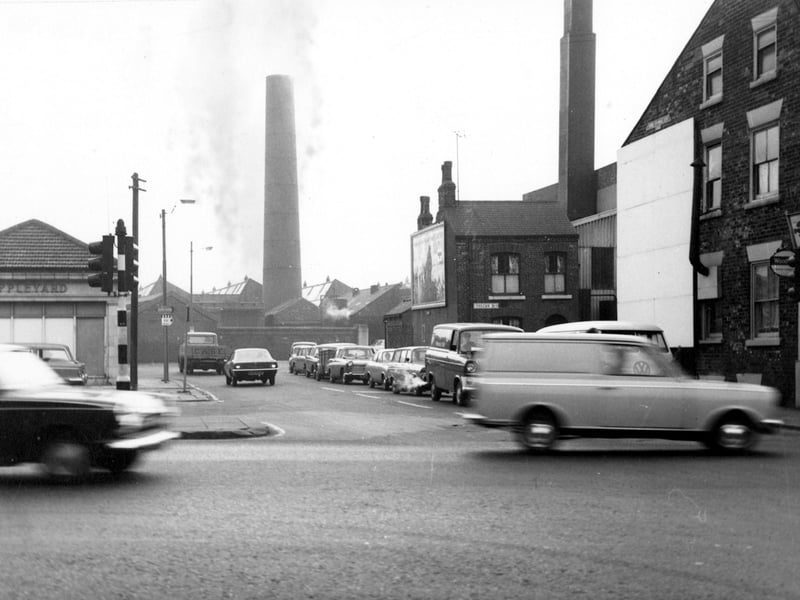 A view looking east from North Street to Sheepscar Street South. On the left is Appleyard of Leeds Ltd. In the distance are two large brick chimneys. Traffic is queuing at traffic lights in the centre of the photo. On the right are the terraced houses of Vulcan Street. Pictured in November 1968. 