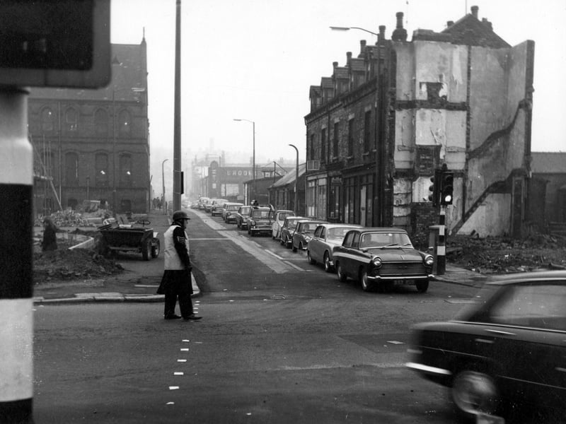 Looking north-east down Barrack Street from the junction with Meanwood Road, where a policeman in a crash helmet is directing traffic. On the left is a building site with a dumper truck on it. A house has been demolished at the end of Barrack Street, on the right. Pictured in November 1968.