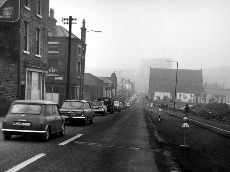 Looking south-west along Barrack Street, with St Clement's Place on the left. Further down is the empty and boarded up Elsanco Works. A row of cars wait at Sheepscar Street traffic lights.