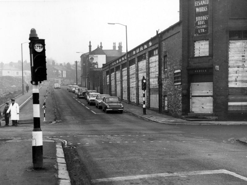 Looking north-east up Barrack Street from its junction with Sheepscar Street North, where a queue of cars wait at traffic lights. On the right is the empty Elsanco Works, now boarded up. On the left is a crossing guard with two children. Pictured in November 1968.