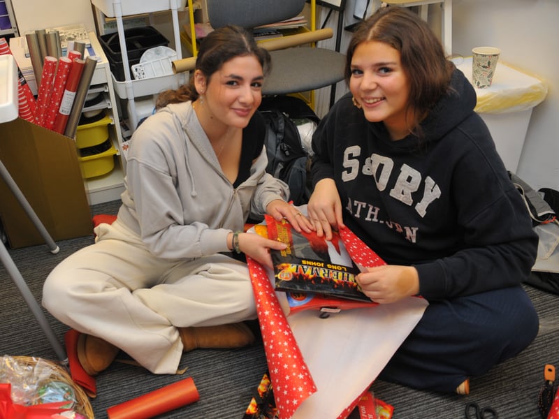 Evie Shapero and Angel Katz work together to wrap presents.