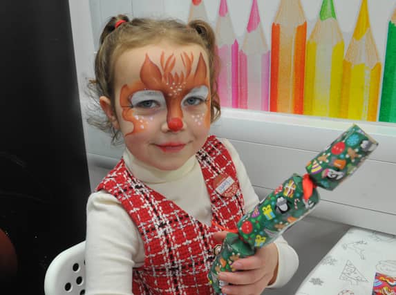 Blakeley Lister, eight, helps with arranging the gifts after having her face painted.
