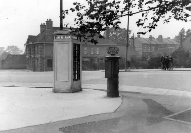 A telephone kiosk and letter box on corner of Harrogate Road and Montreal Avenue. Over the road is the Mexborough Arms public house. A young girl stands at a tram stop while a group of men are chatting by the side of the road. Pictured in July 1936.