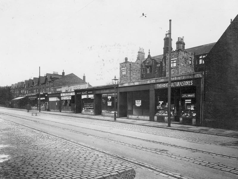 Newton Parade opposite St. Mary's Road in October 1934. Single storey shop units with date 1931. Variety of businesses, including Lewis's catering. Road part tarmac, part cobbles, with tramlines.
