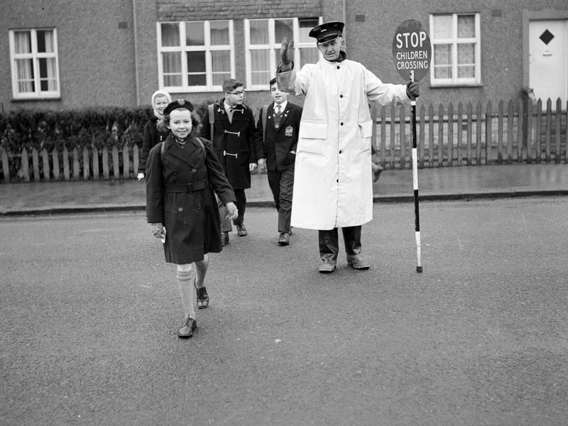 Traffic warden and lollipop man William Withnell shows children across Colinton Mains Road to Oxgangs Primary School in March 1963.