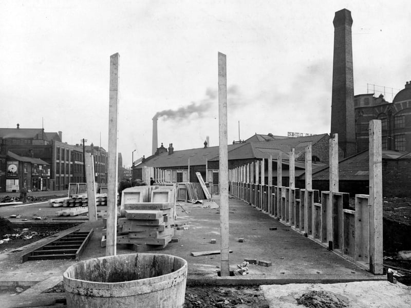 The construction of a British Restaurant, a cheap public eating place during World War II, on Whitehall Road. Wooden posts, concrete slabs and a ladder are visible. S. Batt & Co. Ltd. petrol station, Petty & Sons Ltd. printers and an advertisement urging to save coal can be seen. Pictured in the November 1942.