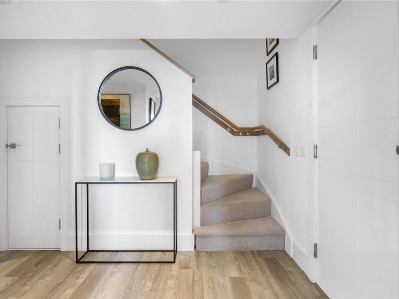 Upon entering the apartment, a welcoming hallway with built-in under-stair storage leads to the main living area.
