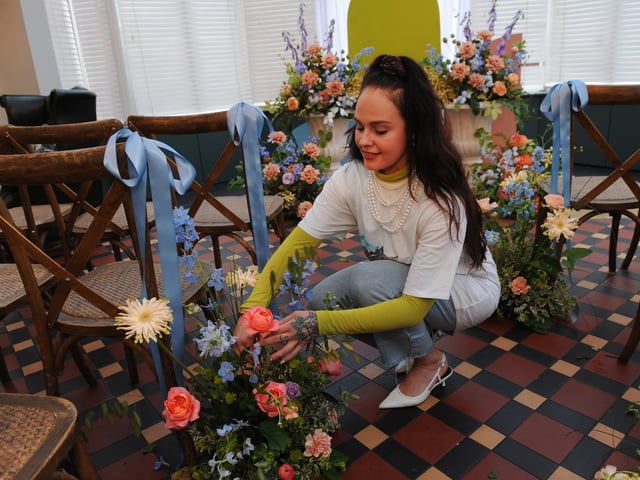 Dottie Hall of Hyde Park Flower Club finishes one of her aisle arrangements.