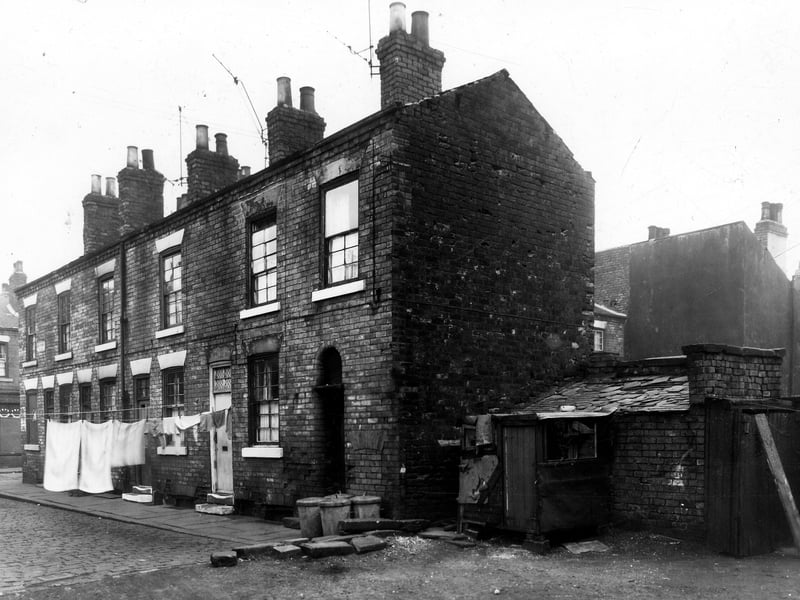 This is looking at part of Greystone Place. On the left, is Greystone Street, then at the corner is 11 Greystone Place. The houses seen behind on the right are on Wellington Place. The area in the foreground was to the back of houses which went through to Wordsworth Street. A wall had once divided Greystone Place from this ground, the remains of the wall can be seen near the dustbins and the boundary line.