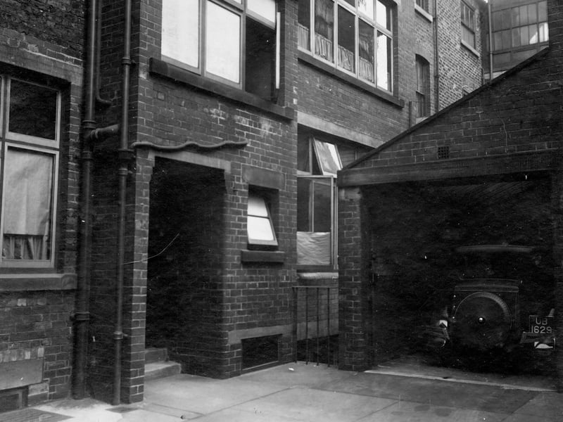 Park Cross Street in November 1931. In focus is a view of a three-storey building with basement. Garage with parked car on right.