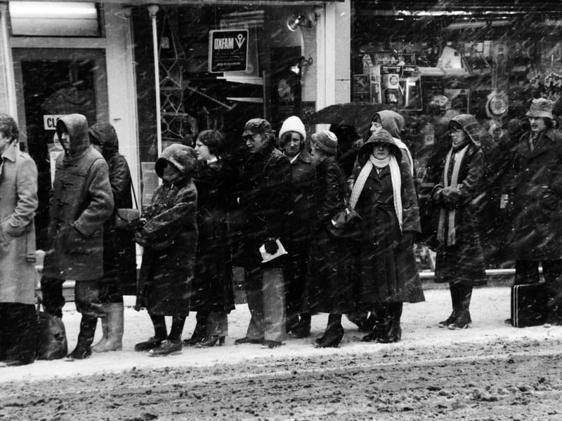 The snow lashes down on people queuing for a bus to transport them home as the city evening rush hour begins on Boar Lane in February 1979.