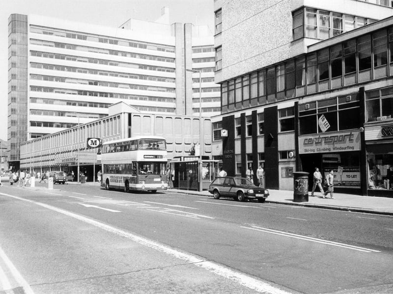 Woodhouse Lane showing the Merrion Centre. Newarke Wools is on the right followed by a shop to let that was previously occupied by Centresport. Lloyds Bank is at the end of the row before the entrance to the shopping centre, with Morrisons supermarket following on from this. Towering above it in the background, left, is the office block Merrion House.