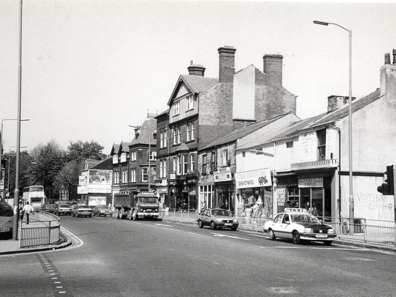 Looking north-west along Headingley Lane from Hyde Park Corner. The junction with Hyde Park Road is on the left. On the far right is the edge of The Hyde Park public house. Shops following on from this include Snipperfields Circus hairdressers, a cane furniture and basketware store and La Paprika coffee bar.