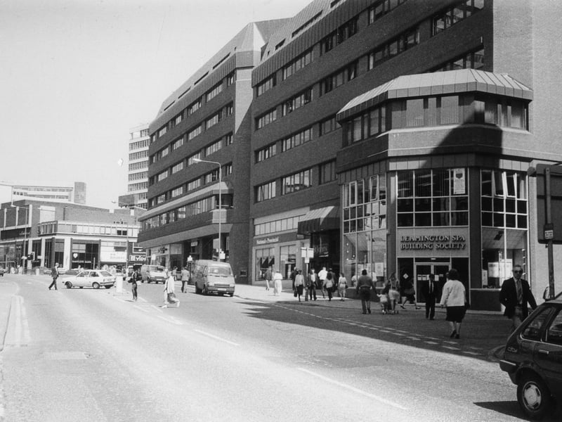 Albion Street showing St. John's Shopping Centre, opened in 1985. The Leamington Spa Building Society and National Provincial Building Society are among businesses occupying premises around the outside. On the left, past the junction with Merrion Street, is the Merrion Centre on Woodhouse Lane.