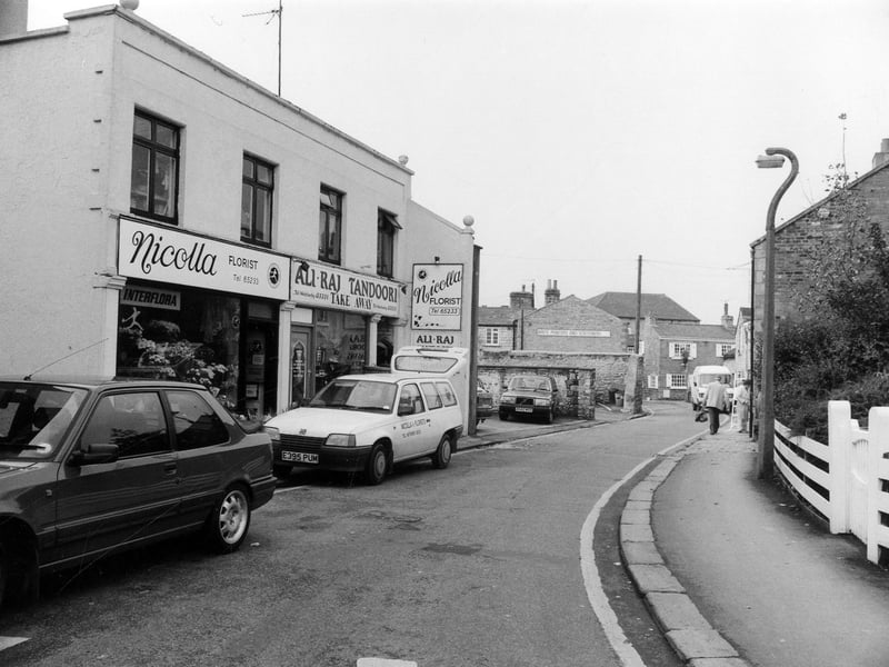 Looking north-west along Bank Street showing Nicolla, Florist, on the left at no. 1 followed by Ali-Raj Tandoori takeaway at no. 3. Further along is Write Printers and Stationers which faces onto Church Street.