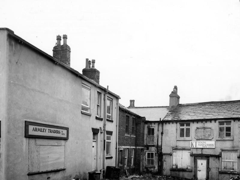 Stocks Hill in September 1982. On the left, no. 13 is Armley Traders second-hand furniture showroom. The darker building in the middle is no. 15. On the right, no. 17, KT builders and fencing manufacturers, has lower windows boarded up and rubble piled up outside. 